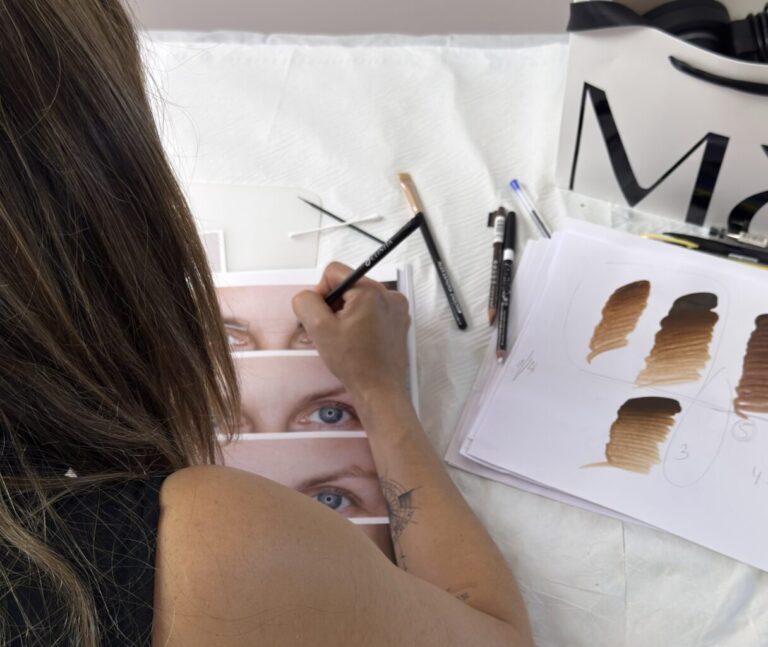 Mónica Lorenzo practicando trazos pelo a pelo sobre fotografías de cejas impresas